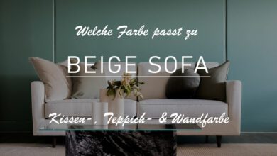 Einblick in ein Wohnzimmer mit beigefarbenen Sofa. Dekoriert wurde dieses mit grünem und olivfarbenem Kissen. Im Hintergrund ist eine tannengrüne Wand. Vor dem Sofa befindet sich ein marmorierter Tisch mit Glasplatte. Das Bild ist leicht abgedunkelt, um den Titel zu sehen: Welche Farbe passt zu beige Sofa?
